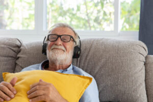 A smiling and content man wearing headphones shows the emotional power of therapeutic music.