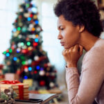 A Black woman in her 50s expresses feelings of grief over the loss of a loved one while she sits near a Christmas tree in the background
