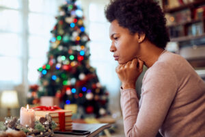 A Black woman in her 50s expresses feelings of grief over the loss of a loved one while she sits near a Christmas tree in the background