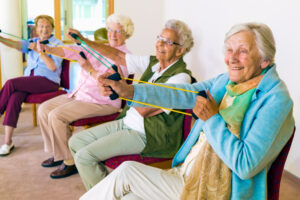 Four senior women stretch exercise bands to stay fit at an assisted living community