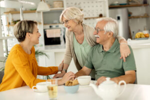 Sitting at a kitchen table, an adult daughter talks to her older parents about the importance of advance planning.